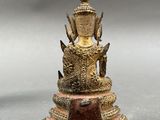 an old bronze statue of a buddha sitting on a pedestal