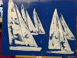trois voiliers peints sur une toile bleue posée sur un chevalet