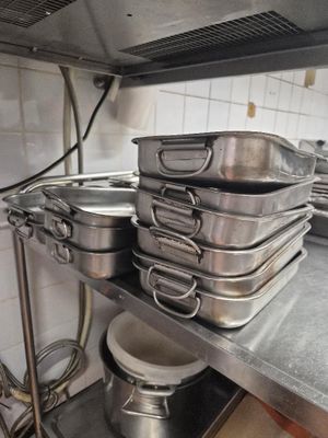 several pots and pans are stacked on a metal shelf in a kitchen