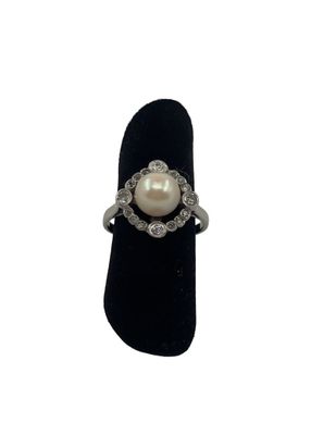 une photo d'une bague sertie d'une perle et de diamants, posée sur un présentoir en velours noir