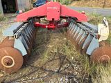 a red tractor with a large blade attached to it ' s back