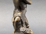 a bronze statue of a man sitting on top of a rock