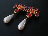 pair of red and white earrings with pearls on a black surface