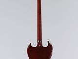 a red guitar hanging from a string on a white wall