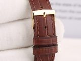 a close up of a brown leather watch strap with a gold buckle