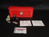 des figurines représentant un homme et une femme debout à côté d'une boîte rouge
