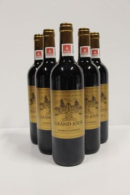 four bottles of red wine are lined up on a white surface
