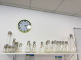 une horloge accrochée au mur au-dessus d'une étagère sur laquelle sont posés des verres