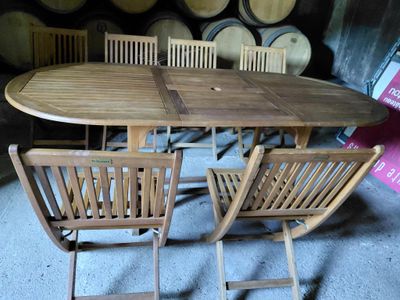 une table et des chaises dans une cave à vin, avec des tonneaux en arrière-plan