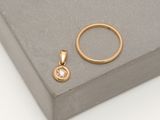 an image of a gold ring and a diamond pendant on a grey surface