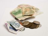 une liasse de billets posée sur une table à côté de quelques pièces de monnaie
