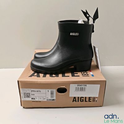 une photo représentant une paire de bottes de pluie noires posées sur une boîte