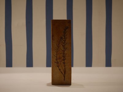 a small vase with a plant on it on a table
