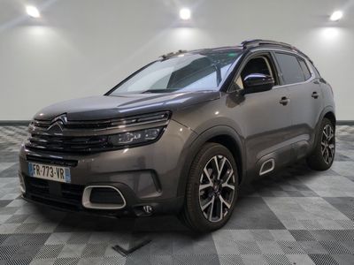 Une Citroën grise est garée dans une pièce au sol carrelé