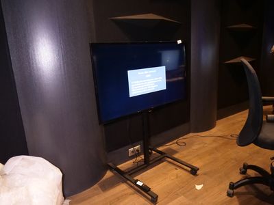 un téléviseur à écran plat posé sur un support dans le coin d'une pièce