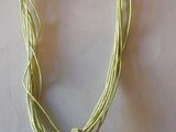 collier composé d'un coquillage, d'un cordon vert et d'un pendentif doré