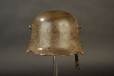 an old helmet on a metal stand against a gray background