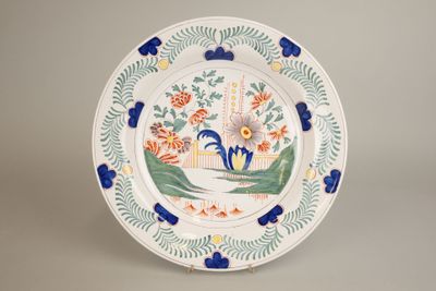 Grand plat creux rond en faïence à décor floral polychrome. …