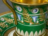a green and gold cup and saucer sitting on a plate