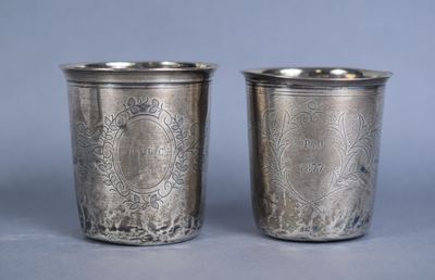 two silver cups with designs on them sitting on top of a table
