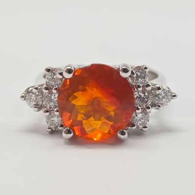 une bague sertie d'une opale de feu orange et de diamants, sur fond blanc