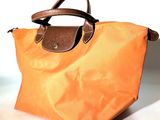un sac orange muni d'une poignée marron posé sur une table