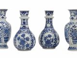 quatre vases bleus et blancs sont alignés sur un fond blanc