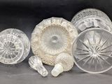 several clear glass dishes and cups are sitting on a black surface