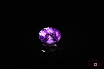 a close up of a purple stone on a black surface