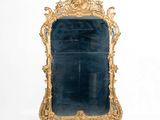 un grand miroir avec un cadre doré accroché au mur