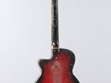 a red guitar hanging from a string on a white wall