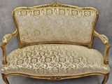a gold and white couch sitting on top of a wooden floor