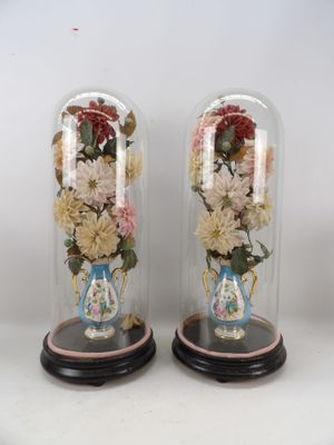 deux vases contenant des fleurs, placés sous une cloche en verre