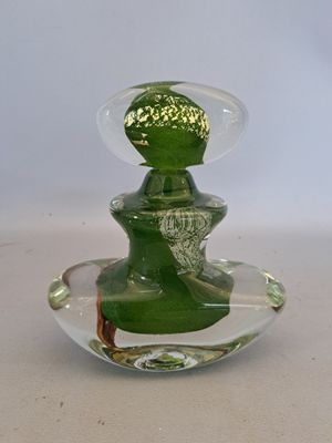 a green glass vase with a green lid on a white table