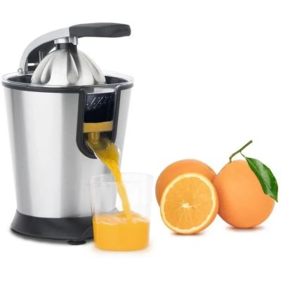 du jus d'orange versé dans un extracteur de jus à côté d'oranges