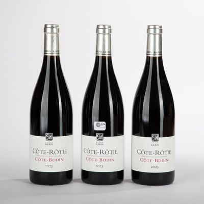 trois bouteilles de vin rouge posées sur une table blanche