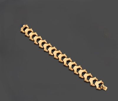 gros plan d'un bracelet en or sur une surface noire