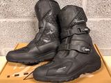 the pair of black motorcycle boots are sitting on a cardboard box