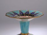 un vase bleu et or posé sur une surface blanche