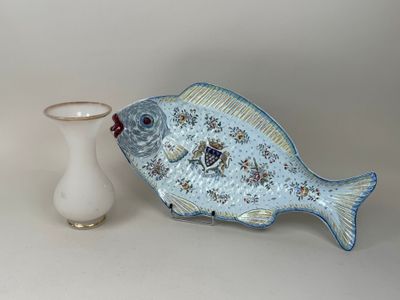 un vase blanc posé à côté d'un poisson bleu sur une table