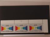 Trois timbres de couleurs différentes sont accrochés sur un mur blanc.