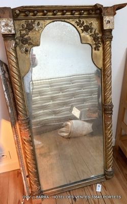 un grand miroir posé sur un parquet, à côté d'un lit