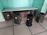 three trash cans and a bench in the corner of a room