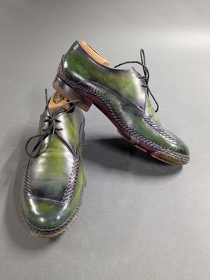 pair of men ' s shoes with green and purple paint on them