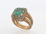 a gold ring with an oval emerald stone surrounded by diamonds
