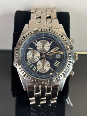 silver and black watch on display on black surface with white background