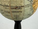 a small globe on a black stand on a white surface