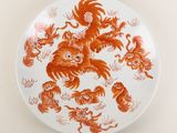 une assiette orange et blanche sur laquelle est représenté un groupe d'animaux