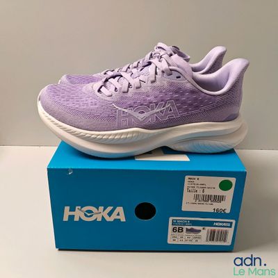 the purple and white shoe is sitting on top of a blue box
