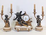 trois bougies et une horloge posées sur une table